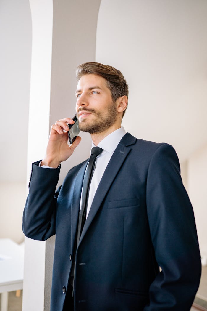 Confident businessman in a suit having a phone conversation indoors.